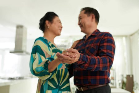 Téléchargez les photos : Heureux couple vietnamien âgé appréciant la danse romantique à la maison - en image libre de droit
