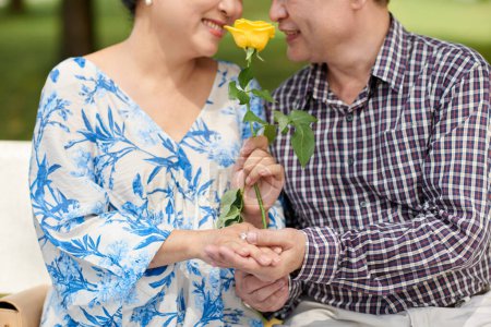 Foto de Imagen recortada de pareja mayor recién casada con rosa sonriendo y mirándose el uno al otro - Imagen libre de derechos