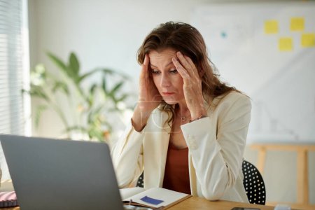 Téléchargez les photos : Stressé femme entrepreneur mature rapport de lecture avec de mauvaises performances de l'entreprise - en image libre de droit