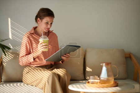 Téléchargez les photos : Femme d'affaires mature boire du café matcha lors de la lecture du rapport - en image libre de droit