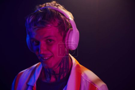 Téléchargez les photos : Portrait de DJ souriant dans un casque mélangeant musique dans une boîte de nuit - en image libre de droit