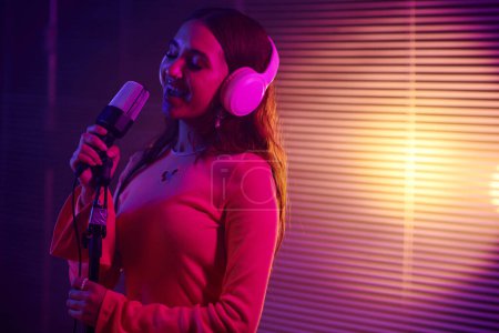 Téléchargez les photos : Jeune chanteuse jouant avec une nouvelle chanson à la soirée - en image libre de droit