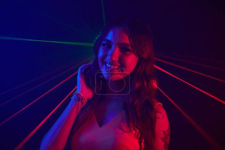 Photo for Portrait of smiling young woman dancing in neon lights of night club - Royalty Free Image