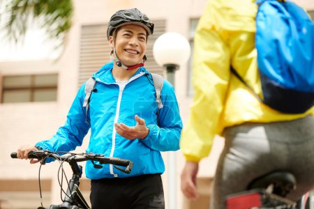 Téléchargez les photos : Portrait de jeune cycliste vietnamien heureux parlant à sa petite amie après le trajet - en image libre de droit