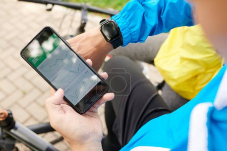 Téléchargez les photos : Mains de cycliste vérifiant son activité via application sur smartphone - en image libre de droit