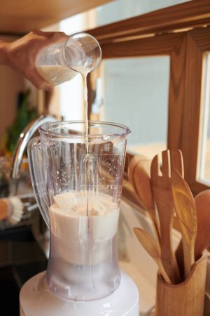 Téléchargez les photos : Homme versant du lait non journal dans un mélangeur avec lors de la fabrication de smoothie - en image libre de droit
