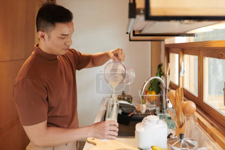 Photo for Man filling plastic bottle with protein shake he made for breakfast - Royalty Free Image