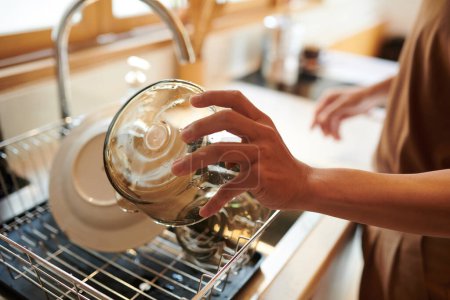 Téléchargez les photos : Mains de l'homme rinçant des bols en verre sous l'eau du robinet après le petit déjeuner - en image libre de droit