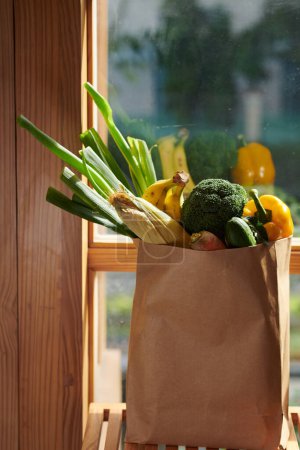 Téléchargez les photos : Grand paquet de papier de fruits et légumes frais sur le rebord de la fenêtre - en image libre de droit