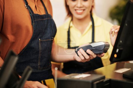 Foto de Propietario del café mostrando al nuevo trabajador cómo imprimir recibos después de aceptar el pago con tarjeta - Imagen libre de derechos