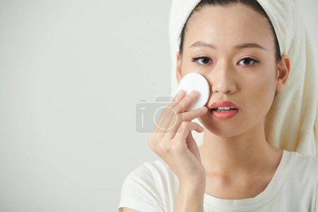 Téléchargez les photos : Portrait de jeune femme appliquant un toner visage avec un coton pour restaurer le pH de la peau - en image libre de droit