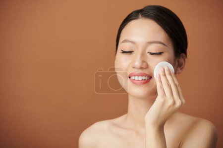 Téléchargez les photos : Portrait de jeune femme essuyant le maquillage à l'eau micellaire - en image libre de droit