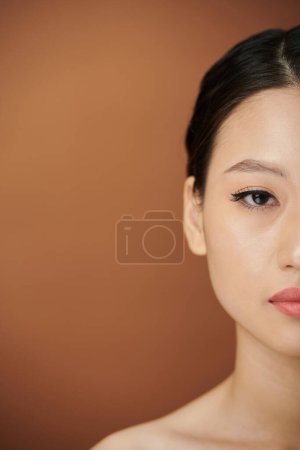 Photo for Half face of young Asian woman with eye liner and lip tint looking at camera - Royalty Free Image