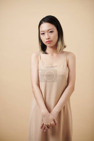 Foto de Retrato de mujer asiática tímida en vestido de seda mirando a la cámara - Imagen libre de derechos
