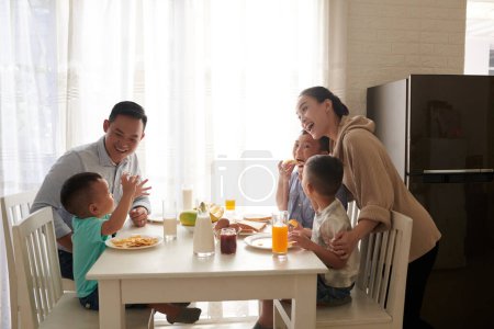 Téléchargez les photos : Happy joyeuse famille asiatique de cinq manger savoureux petit déjeuner à la table de cuisine - en image libre de droit