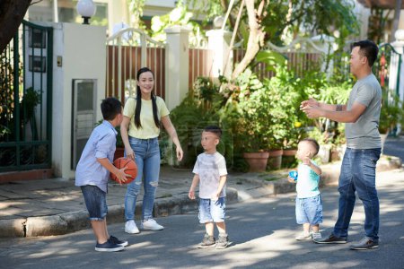 Photo for Happy family of five playing with ball together in front of house - Royalty Free Image