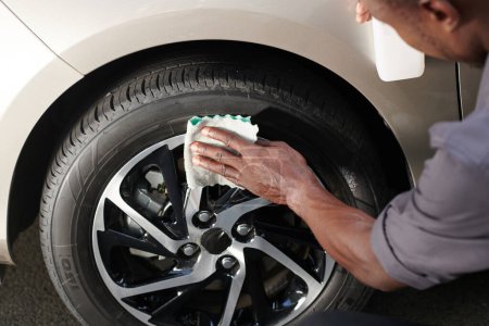 Photo for Close-up image driver cleaning aluminum wheels with soft cloth to make it shine - Royalty Free Image