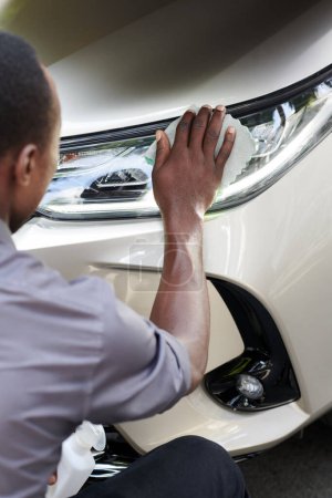 Photo for Car driver polishing headlight with soft cloth to wipe off dust - Royalty Free Image