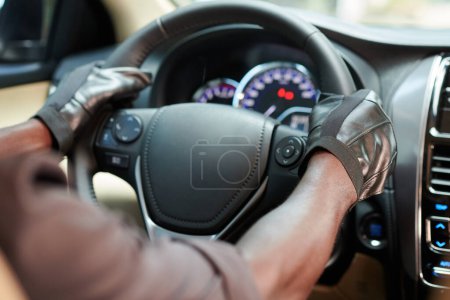 Téléchargez les photos : Image rapprochée du conducteur portant des gants en cuir lors de l'équitation automobile en ville - en image libre de droit