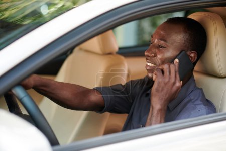 Foto de Positivo hombre negro hablando por teléfono al conducir a la oficina - Imagen libre de derechos