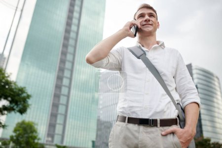 Foto de Retrato de un joven de camisa blanca llamando al servicio de taxi para pedir un coche - Imagen libre de derechos