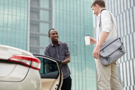 Téléchargez les photos : Chauffeur personnel souriant ouvrant la porte de voiture pour le passager - en image libre de droit