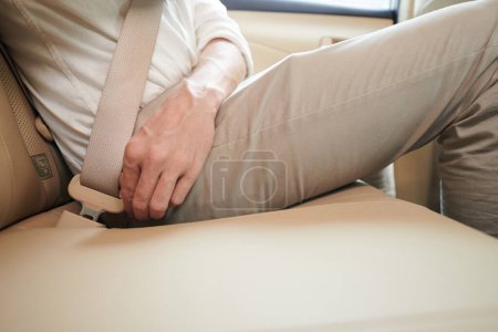 Photo for Close-up image of man wearing belt when riding in backseat of taxi car - Royalty Free Image