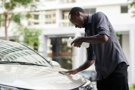 Foto de Propietario del coche limpiando la capucha con detergente para eliminar las manchas de insectos de la capucha - Imagen libre de derechos