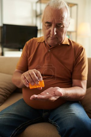 Photo for Aged man suffering from disease taking tablets or supplements - Royalty Free Image