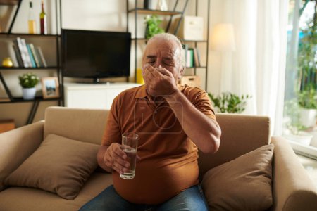 Photo for Senior man taking painkillers with glass of water - Royalty Free Image