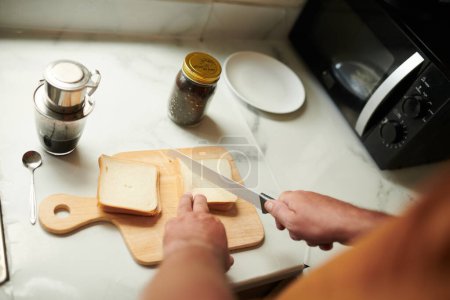Photo for Hands of man cutting bread in triangles when making sandwiches for breakfast - Royalty Free Image