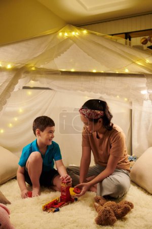 Photo for Mother and kid playing together inside big tent in nursery room - Royalty Free Image