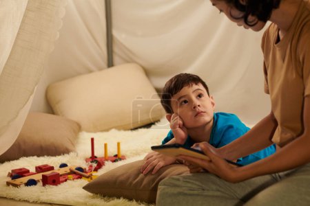 Photo for Curious little boy looking at his reading mother when they are spending weekend together - Royalty Free Image