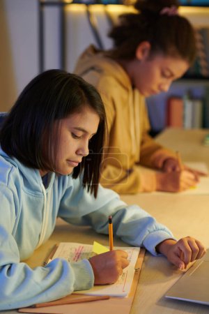Photo for Schoolgirls preparing for upcoming test late at night - Royalty Free Image