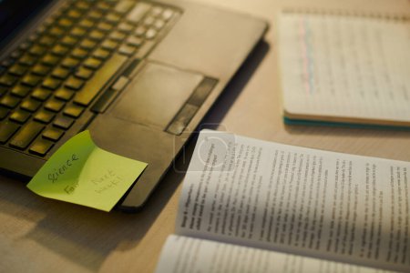 Photo for Opened book and laptop with bright sticky note on desk - Royalty Free Image
