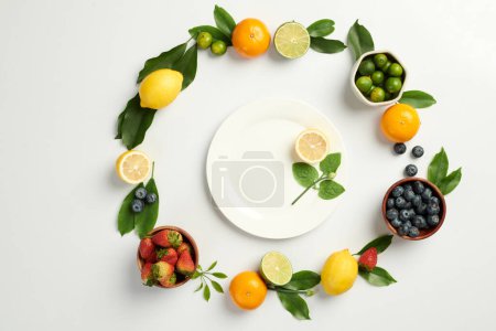 Photo for Berries and citrus fruits around plate with slice of lemon - Royalty Free Image