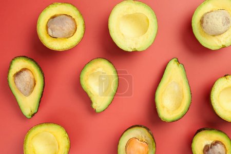 Photo for Cut fresh ripe avocados on red background - Royalty Free Image