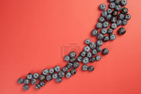Photo for Big fresh blueberries scattered on red table, top view - Royalty Free Image