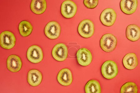 Téléchargez les photos : Tranches de kiwi juteux frais sur table rouge, vue sur le dessus - en image libre de droit