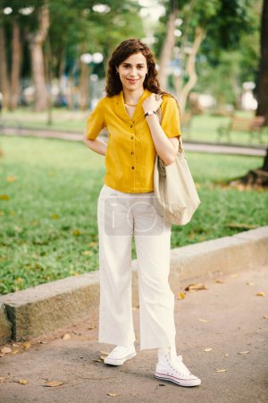 Photo for Portrait of smiling young woman walking in city park - Royalty Free Image