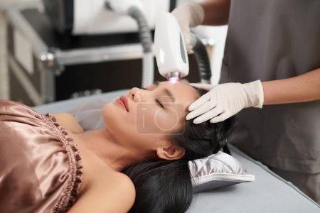 Photo for Woman getting forehead hair removal with alexandrite laser - Royalty Free Image