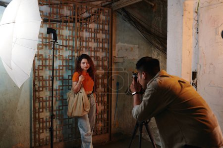 Téléchargez les photos : Jeune homme photographier fille dans vieux bâtiment pour magasin de vêtements en ligne - en image libre de droit
