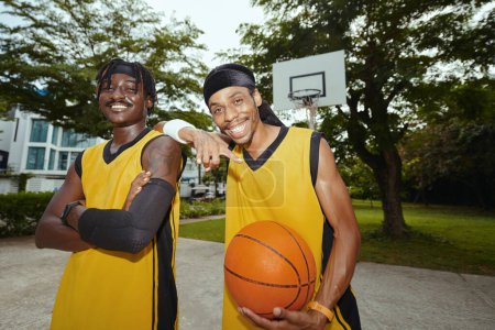 Téléchargez les photos : Portrait de joyeux joueurs de streetball excités en uniforme posant au court extérieur - en image libre de droit