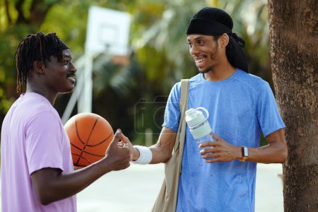 Photo for Black men having secret handshake, friends meeting to play basketball - Royalty Free Image