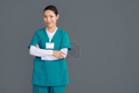 Photo for Studio portrait of rehabilitation nurse in green uniform standing with arms crossed - Royalty Free Image