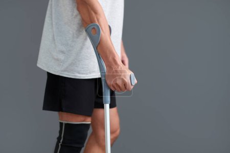 Foto de Imagen recortada del hombre con la pierna lesionada apoyada en la muleta al caminar - Imagen libre de derechos
