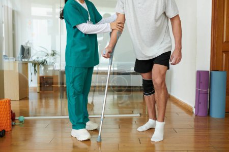 Foto de Imagen recortada del paciente del centro de rehabilitación caminando con muleta bajo control de la enfermera médica - Imagen libre de derechos