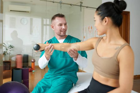Photo for Young woman rebuilding arm strength at rehabilitation session with therapist - Royalty Free Image