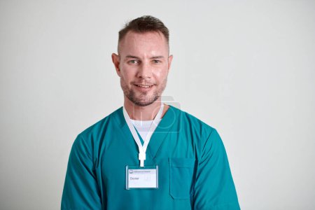 Téléchargez les photos : Portrait de médecin mature souriant avec badge portant des blouses vertes - en image libre de droit