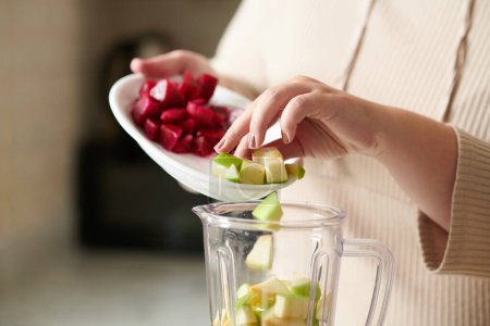 Photo for Close-up image of woman adding green apple and dragonfruit in blender when making smoothie - Royalty Free Image